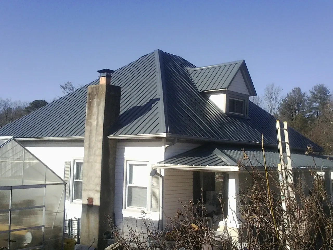 Dark blue standing seam metal roof on a white farmhouse with dormer — Slate & Tile Roof Repair by Roofing Brothers in Randolph